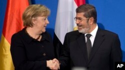 German Chancellor Angela Merkel, left, and President of Egypt Mohammed Morsi, right, shake hands after a joint press conference at the chancellery in Berlin, Germany, Wednesday, Jan. 30, 2013. (AP Photo/Michael Sohn)