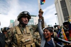 A woman cries in front of soldiers guarding a street during a march of supporters of former President Evo Morales in downtown La Paz, Bolivia, Nov. 15, 2019.