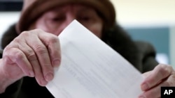 A voter casts her ballot at a polling station in Zagreb, Croatia, Sunday, Jan. 5, 2020. 