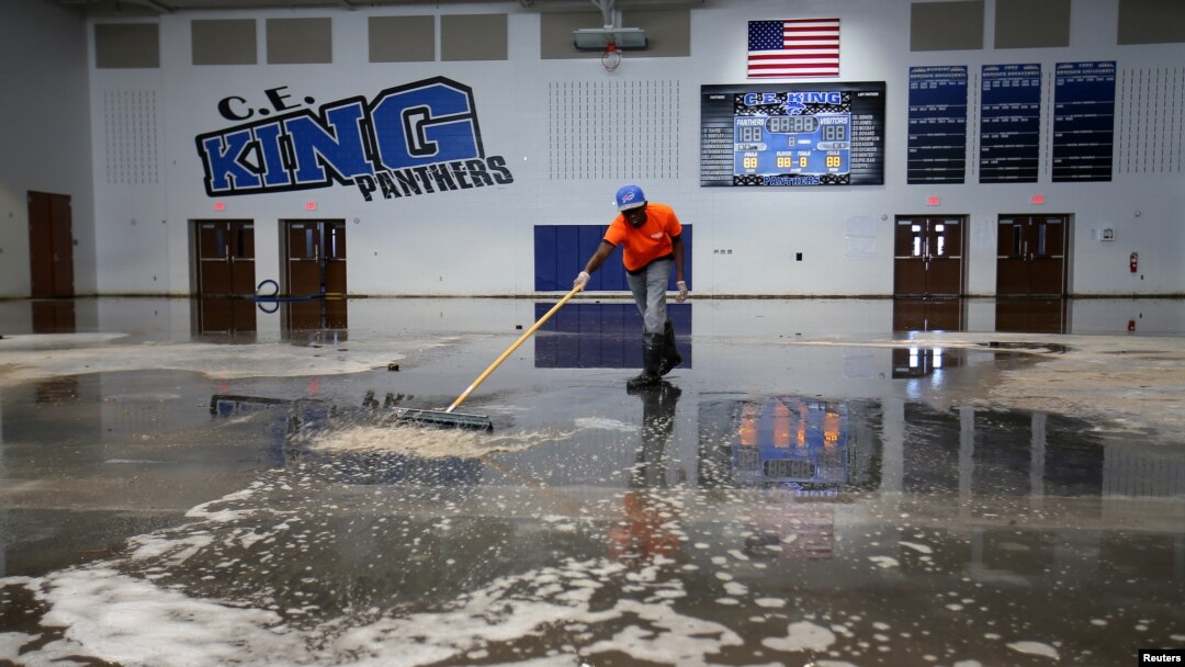 FILE - Darius Moses works removing water from the gymnasium at C.E. King High School following the aftermath of tropical storm Harvey in Houston, Texas, Sept. 8, 2017.