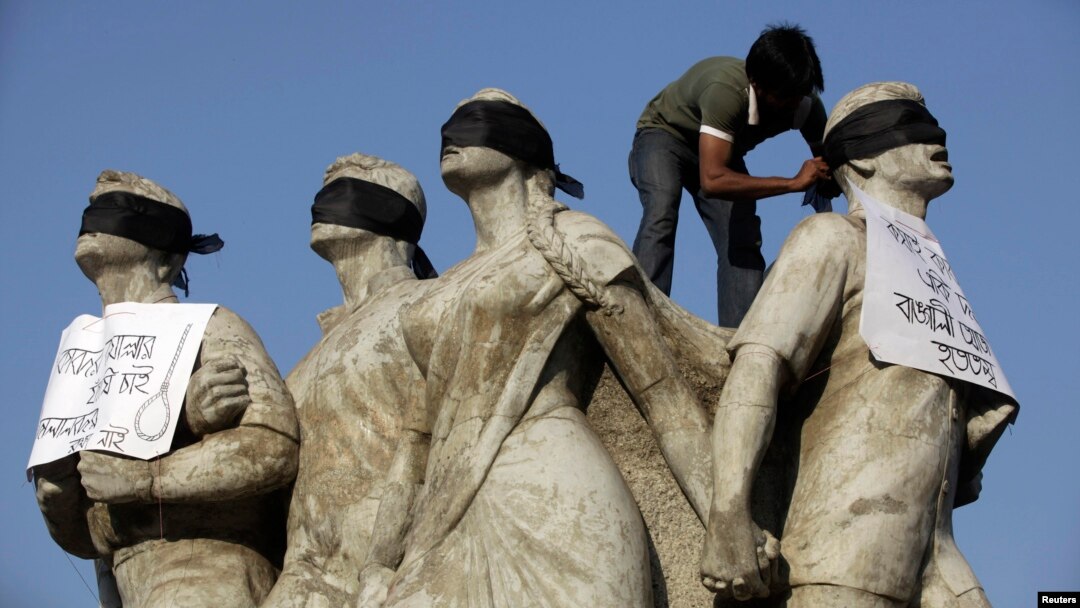 FILE- A student activist puts black scarves on the eyes of Shoparjito Shadhinota, a sculpture that represented all sections of people in Bangladesh's liberation War in 1971, demanding capital punishment for Bangladesh's Jamaat-e-Islami senior leader Abdul Quader Mollah, after a war crimes tribunal sentenced him to life imprisonment, in the campus of University of Dhaka, Feb. 6, 2013.
