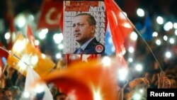 People wave flags and hold a portrait of Turkish President Recep Tayyip Erdogan as they celebrate the ruling AK Party's election win, in Ankara, Turkey Nov. 2, 2015.