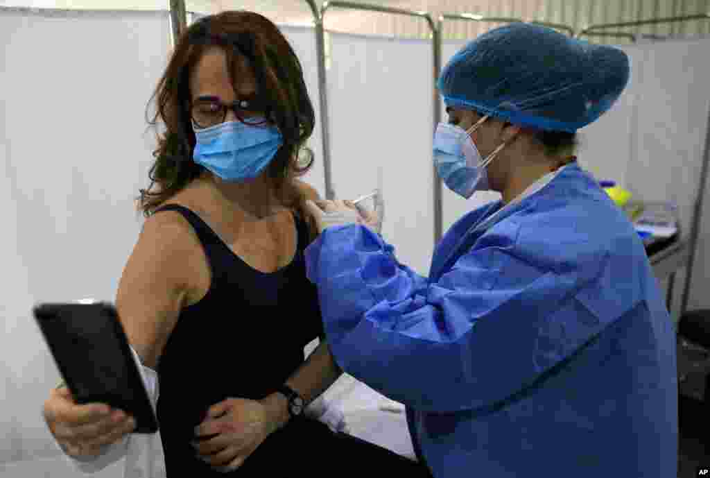 سلفی گرفتن یک زن لبنانی طی دریافت واکسن ویروس کرونا ساخت شرکت فایزر در بیمارستان سنت جورج در بیروت، لبنان