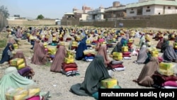 FILE - Afghan burqa-clad women sit after they received ration aid in Kandahar, Afghanistan, May 4, 2016. 