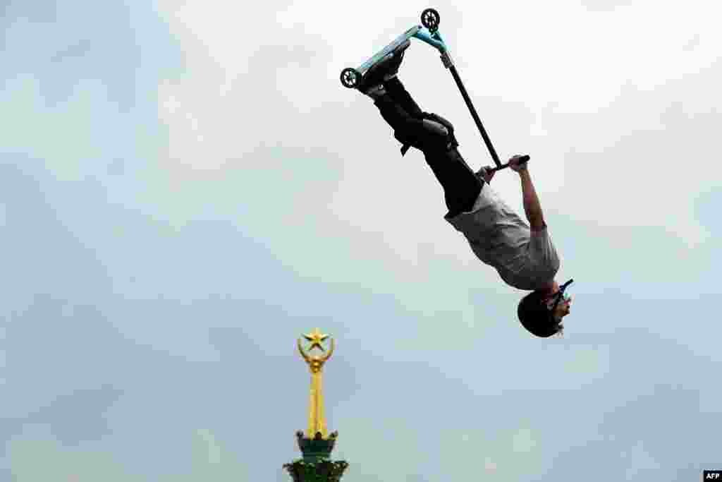 A participant performs a jump with his scooter during a local extreme scooter tournament at the All-Russia Exhibition Center in Moscow, Aug. 1, 2020.