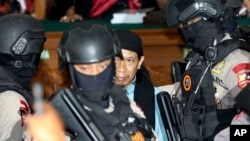 Radical Islamic cleric Aman Abdurrahman, center, is escorted by police officers after his sentence hearing at South Jakarta District Court in Jakarta, June 22, 2018. Abdurrahman was sentenced to death by an Indonesian court.