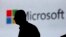FILE - A man is silhouetted as he walks in front of a Microsoft logo at an event in New Delhi, India, Nov. 7, 2017. Microsoft says it’s uncovered new Russian hacking attempts targeting U.S. political groups ahead of midterm elections in November.
