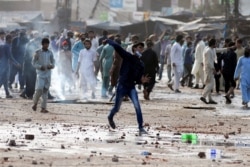 FILE - A supporter of the Tehreek-i-Labaik Pakistan Islamist political party hurls stones toward police during a protest against the arrest of its leader in Lahore, Pakistan, April 13, 2021.