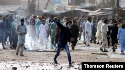A supporter of the Tehreek-e-Labaik Pakistan (TLP) Islamist political party hurls stones towards police during a protest against the arrest of their leader in Lahore, Pakistan April 13, 2021.