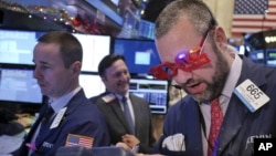 A trader wears glasses in the shape of 2015 while working on the floor at the New York Stock Exchange in New York, Dec. 31, 2014.