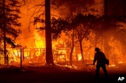 یک آتش‌نشان در مقابل خانه‌ای در حال سوختن در شهرستان پلوماس در شمال کالیفرنیا - ۲۴ ژوئیه ۲۰۲۱