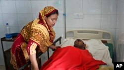 An injured garment worker lies on a hospital bead, as his wife attends to him after a Monday evening boiler explosion at a garment factory owned by export-oriented Multifabs Ltd. at Kashimpur area in Gazipur district, outside capital Dhaka, Bangladesh, July 4, 2017.