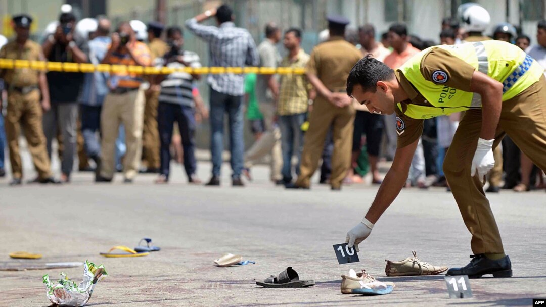A Sri Lankan police officer examines the scene of a shooting in the capital Colombo, where a woman was killed and 13 others were wounded, July 31, 2015.