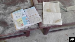 FILE - An alphabet book and a notebook lie on top of an elevated wooden floorboard of a middle school in Let Yet Kone village in Tabayin township in the Sagaing region of Myanmar on Sept. 17, 2022, the day after an air strike hit the school.