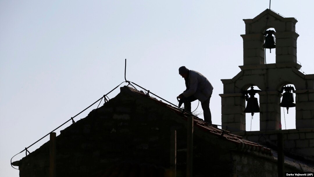 ILUSTRACIJA - Radnik popravlja krov na Crkvi svete nedelje u blizini Svetog Stefana (Foto: AP/Darko Vojinović)