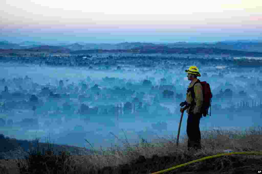FILE - In an Aug. 1, 2020, photo, a firefighter stands watch. La Nina, which often means a busier Atlantic hurricane season, a drier Southwest and perhaps a more fire-prone California, has popped up in the Pacific Ocean, NOAA has announced.