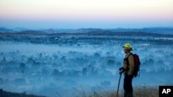 FILE - In an Aug. 1, 2020, photo, a firefighter stands watch. La Nina, which often means a busier Atlantic hurricane season, a drier Southwest and perhaps a more fire-prone California, has popped up in the Pacific Ocean, NOAA has announced.