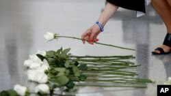 Andrea Chamblee, widow of Capital Gazette journalist John McNamara, places a flower at the foot of the Newseum's Journalists Memorial in Washington, Monday, June 3, 2019.