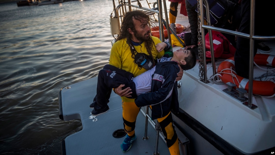 A volunteer carries a young boy after a boat with refugees and migrants sank while crossing the Aegean Sea from Turkey to the Greek island of Lesbos, Oct. 28, 2015. 