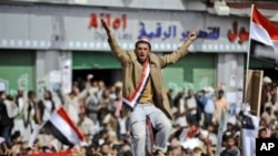 An anti-government protestor sitting on a traffic sign reacts as the bodies of demonstrators who were killed on Friday's clashes with Yemeni security forces, arrive during their funeral procession in Sanaa, Yemen, March 20, 2011