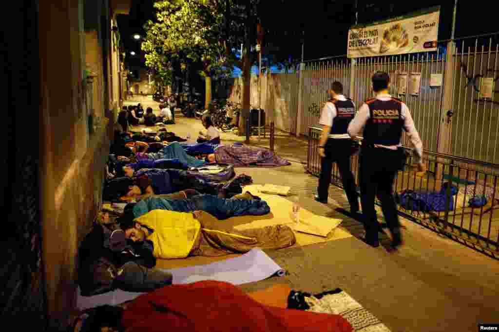 Los oficiales catalanes de Mossos d&#39;Esquadra caminan mientras acampan a la entrada de la escuela primaria ocupada de Reina Violant, una de las mesas designadas, antes del referéndum de independencia del 1 de octubre prohibido en Barcelona. &nbsp; 