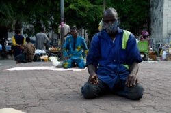 FILE - A Muslim man observes Ramadan prayers along the road in open space of Tinubu Square, wearing a face mask and adhering to social distancing measures to curtail the spread of coronavirus in Lagos, May 13, 2020.