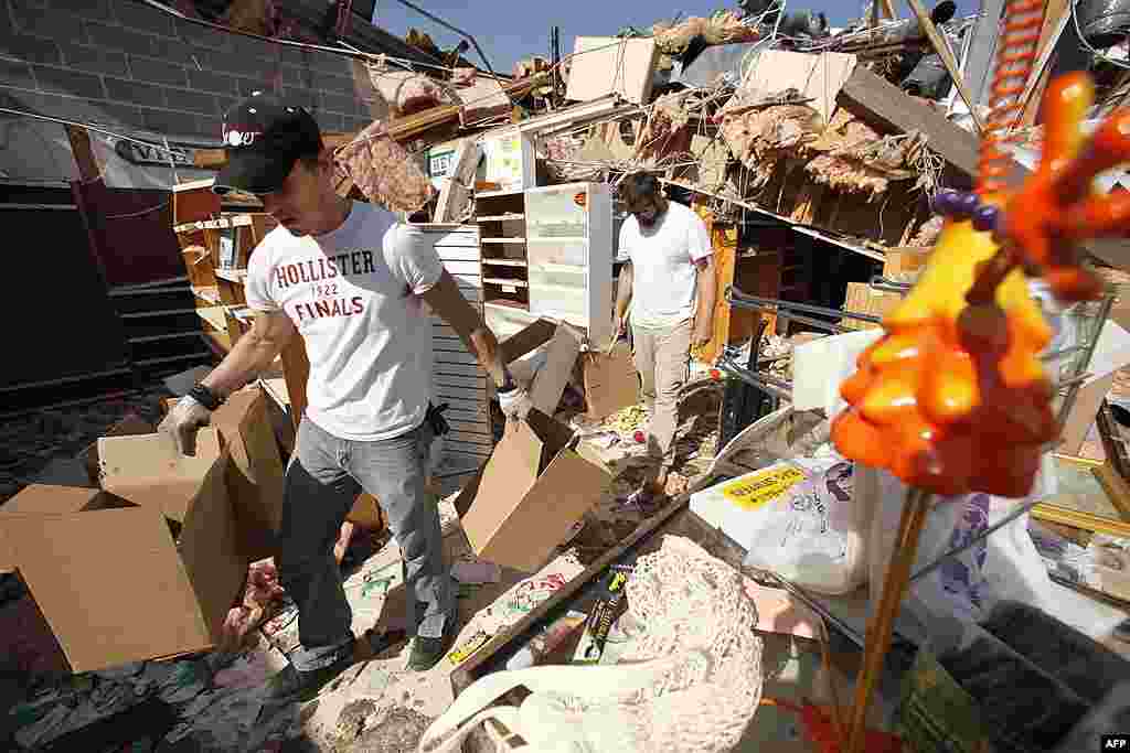 Tim Thress, left, of Branson, and Wake Williams help carry merchandise out of a friend's storm-damaged store in Branson, Missouri, February 29, 2012. (AP)