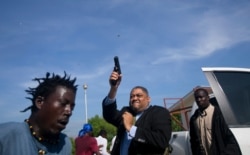 Ruling party Senator Ralph Fethiere fires his gun outside Parliament as he arrives for a vote on the ratification of Fritz William Michel's nomination as prime minister in Port-au-Prince, Haiti, Sept. 23, 2019.