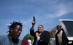 Ruling party Senator Ralph Fethiere fires his gun outside Parliament as he arrives for a vote on the ratification of Fritz William Michel's nomination as prime minister in Port-au-Prince, Haiti, Sept. 23, 2019.
