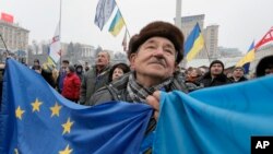 Seorang aktivis pro - Uni Eropa membentangkan bendera Uni Eropa dan Ukraina dalam demonstrasi di Kiev, Ukraina, 20/12/ 2013. 