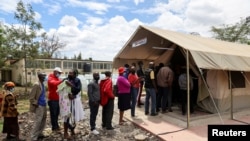 FILE - People stand in line to receive a COVID-19 vaccine, at the Narok County Referral Hospital, in Narok, Kenya, Dec. 1, 2021. 