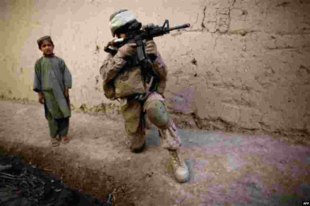 An Afghan boy watches Cpt. Chris Esrey of Havelock, North Carolina, with India, 3rd Battalion 5th Marines, First Marine Division, company, scan the area during a patrol, Wednesday, Nov. 3, 2010, in Sangin, south of Kabul, Afghanistan. (AP Photo/Dusan Vran