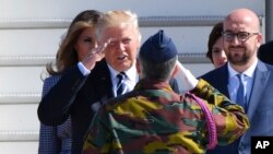 US President Donald Trump, second left, salutes a Belgian soldier as he arrives at Melsbroek Military Airport in Belgium, May 24, 2017. At right is Belgian Prime Minister Charles Michel.