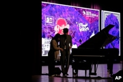 Imlibenla Jamir, 30, left, guides her brother Takosangba Pongen, 27, a blind pianist, to the stage for his performance at the two-day Brillante Piano Festival in Bengaluru, India, Sunday, Sept. 29, 2024. (AP Photo/Aijaz Rahi)