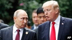 FILE - U.S. President Donald Trump and Russia's President Vladimir Putin talk during a photo session at the APEC Summit in Danang, Vietnam, Nov. 11, 2017. 