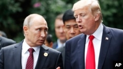 U.S. President Donald Trump and Russia's President Vladimir Putin talk during a photo session at the APEC Summit in Danang, Vietnam, Nov. 11, 2017. 