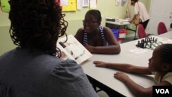 Elaina Howard, who is pursuing her master's degree, reads to her children. The family lives in an apartment provided by a nonprofit which requires residents to improve their lives. (M. Petrillo/VOA) 