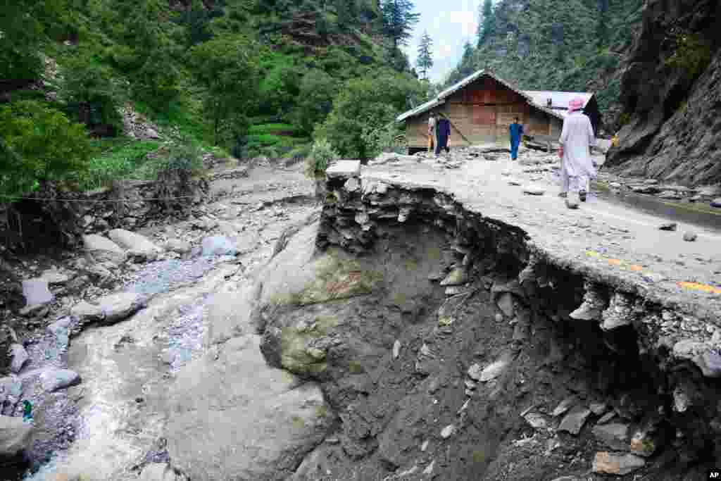 Villagers walk along a road washed away by heavy flooding in the Neelum Valley of Pakistan-controlled Kashmir, July 15, 2019.