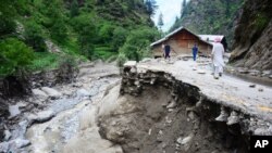 Warga desa berjalan di jalan yang hancur diterjang banjir di Lembah Neelum Valley, di wilayah Kashmir yang dikuasai Pakistan, 15 Juli 2019. 