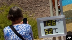 Una mujer toma una fotografía de un termostato que marca 52 grados Celsius y 126 grados Fahrenheit el 7 de julio de 2024, en el Parque Nacional del Valle de la Muerte, California, EEUU. 