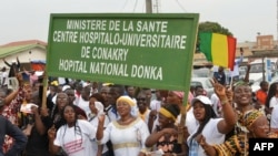 Demonstrators hold a sign reading "Health ministery, Conakry's University Hospital (CHU), Donka's national hospital" as supporters of Guinea's President Alpha Conde take part in a rally in support of the President in Conakry on October 31, 2019. 