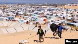 Raseljeni Palestinci, koji su pobjegli iz svojih kuća zbog izraelskih napada, sklonili se u šatorski kamp u Rafi