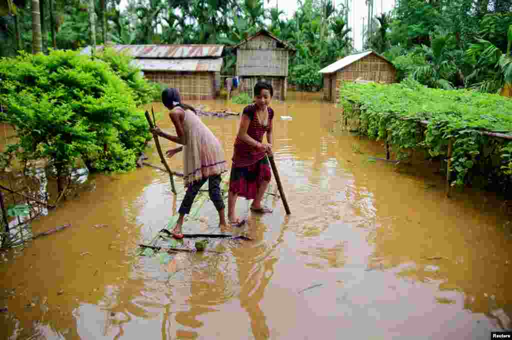 Girls row a makeshift raft past submerged houses in a flood-affected village in the Karbi Anglong district, in Assam, India.