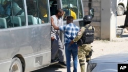 El ex líder golpista Guy Philippe, vestido con un chándal gris, desciende de un autobús en la comisaría de la Policía Nacional de Haití, en Puerto Príncipe, después de ser repatriado desde Estados Unidos el 30 de noviembre de 2023.