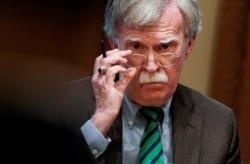FILE - National Security Adviser John Bolton adjusts his glasses during a meeting in the Oval Office at the White House in Washington, April 2, 2019.