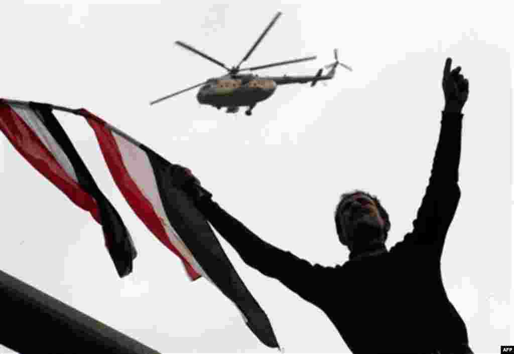 An Egyptian army helicopter patrols above a protester waving Egypt's flags as crowds gather in Tahrir or Liberation Square in Cairo, Egypt, Tuesday, Feb. 1, 2011. More than a quarter-million people flooded into the heart of Cairo Tuesday, filling the city