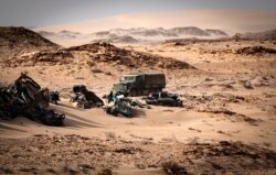 FILE - A Moroccan army vehicle drives past car wreckages in Guerguerat located in the Western Sahara, after an intervention of the royal Moroccan armed forces in the area, Nov. 24, 2020.