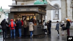 Customers line up at a traditional sausage stand (Wuerstelstand), which are named as intangible cultural heritage by the Austrian UNESCO Commission, in Vienna, Austria, Thursday, Nov. 28, 2024. (AP Photo/Heinz-Peter Bader)