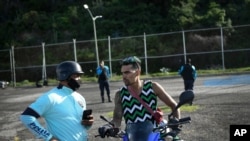 El motociclista Pedro Aldana habla con un policía luego de que los oficiales detuvieran su exhibición en La Guaira, Venezuela. el 30 de enero de 2021. [Foto: AP]