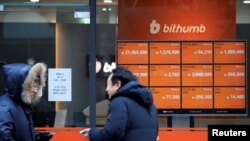 FILE - Men talk in front of an electric board showing exchange rates of various cryptocurrencies at Bithumb cryptocurrencies exchange in Seoul, South Korea, Jan. 11, 2018.